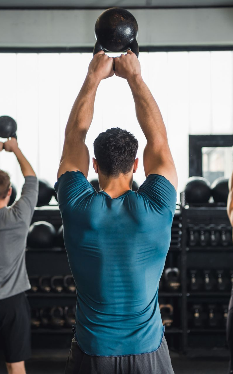 Un homme soulève un poids au-dessus de sa tête dans une salle de sport.