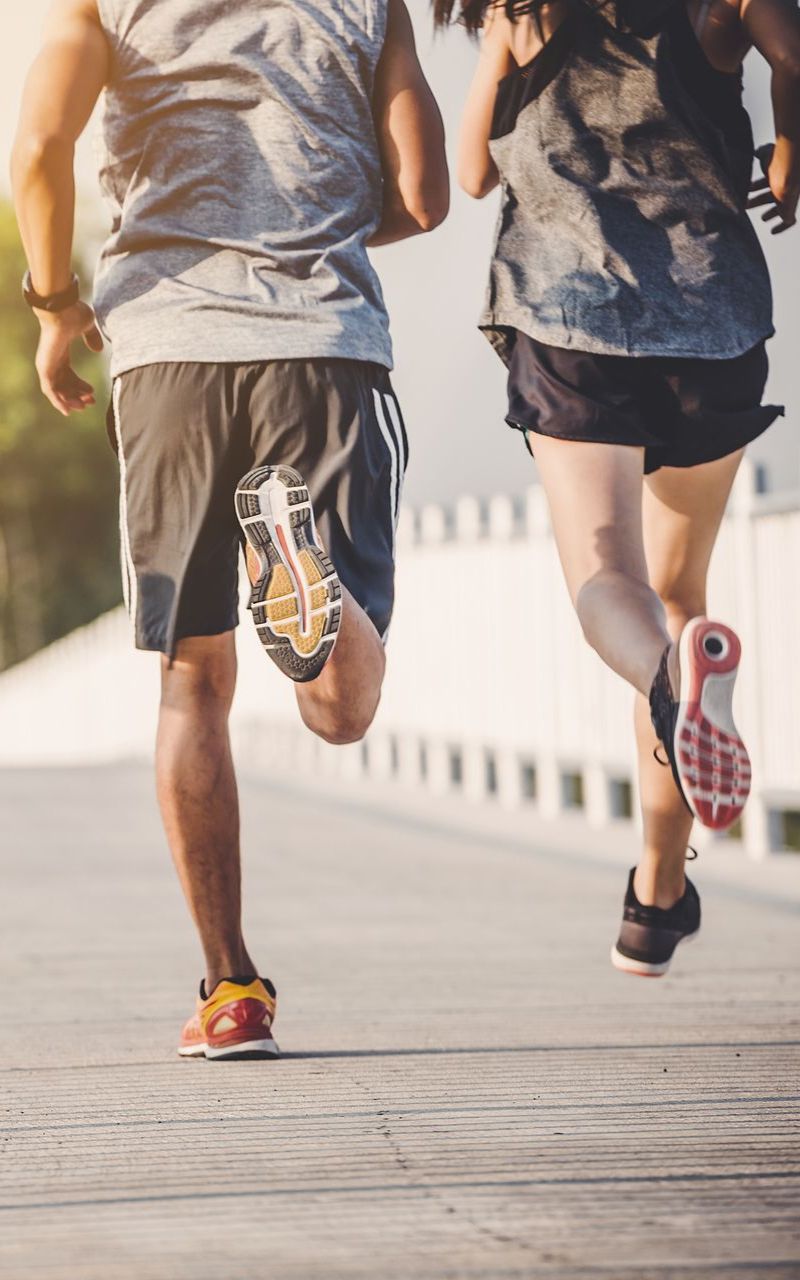 Deux personnes courent dehors sur un pont en tenue de sport.