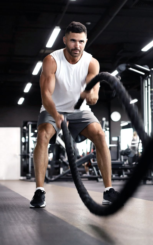 Un homme s'entraîne avec des cordes dans une salle de sport.