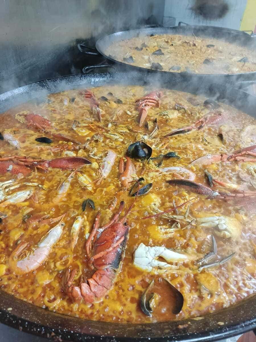 En una cocina se está cocinando una gran paella de mariscos.
