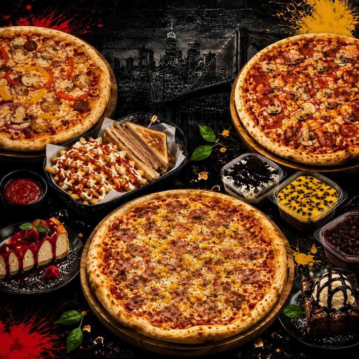 Variedad de pizzas y postres sobre una mesa oscura con detalles de salsa roja y amarilla.