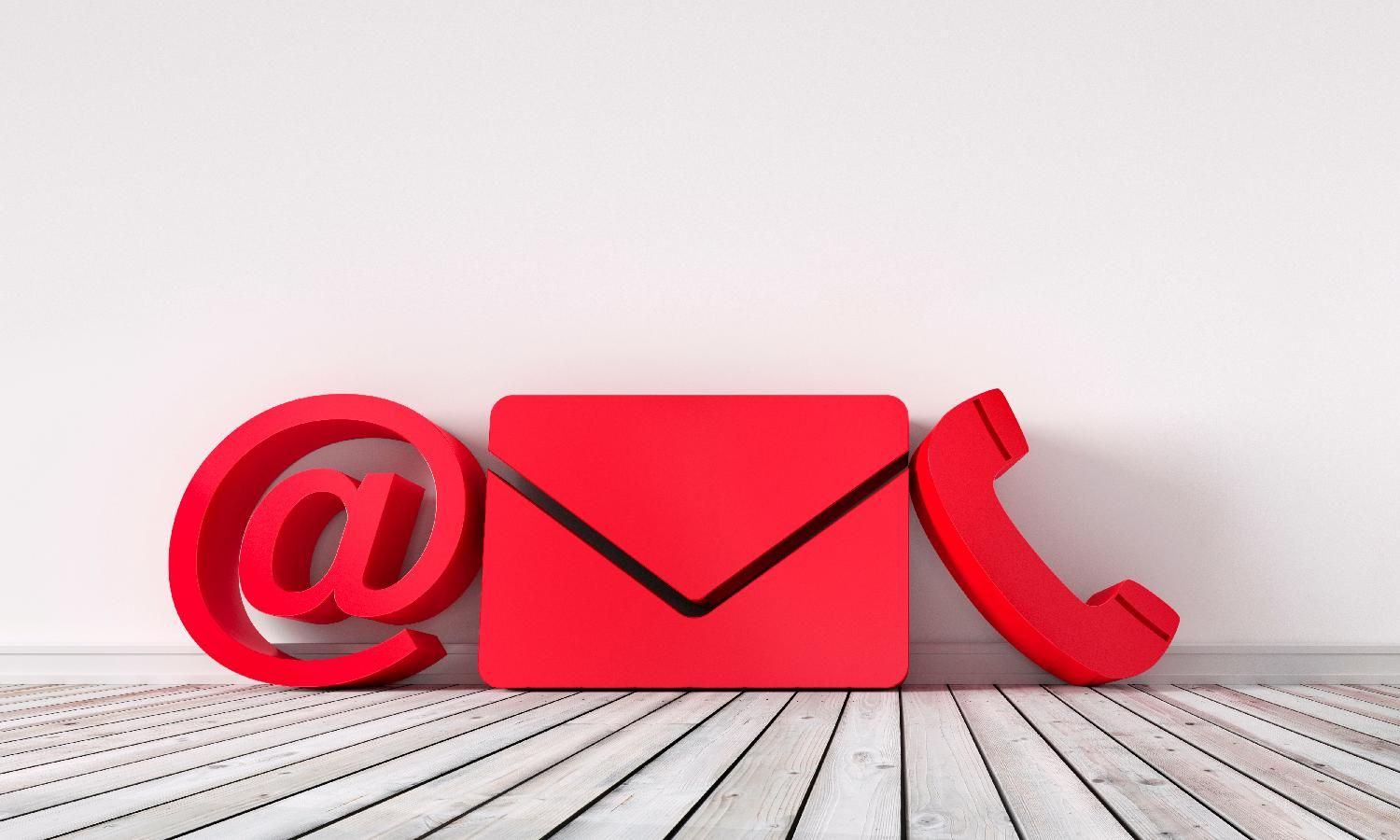 Rotes @-Symbol, Briefumschlag und Telefonsymbol vor weißer Wand und Holzboden. Kontaktsymbole.