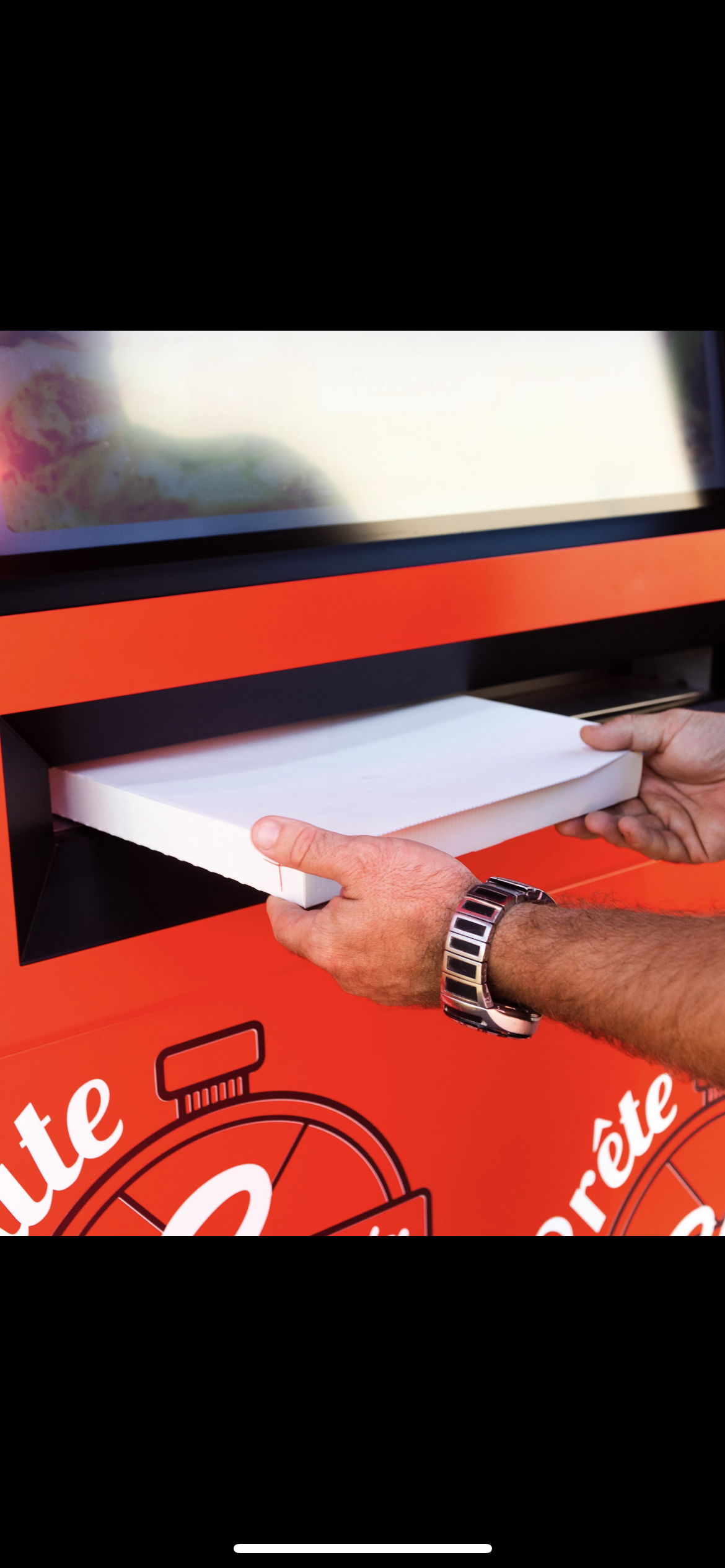 Perosnne qui retire une pizza du distributeur