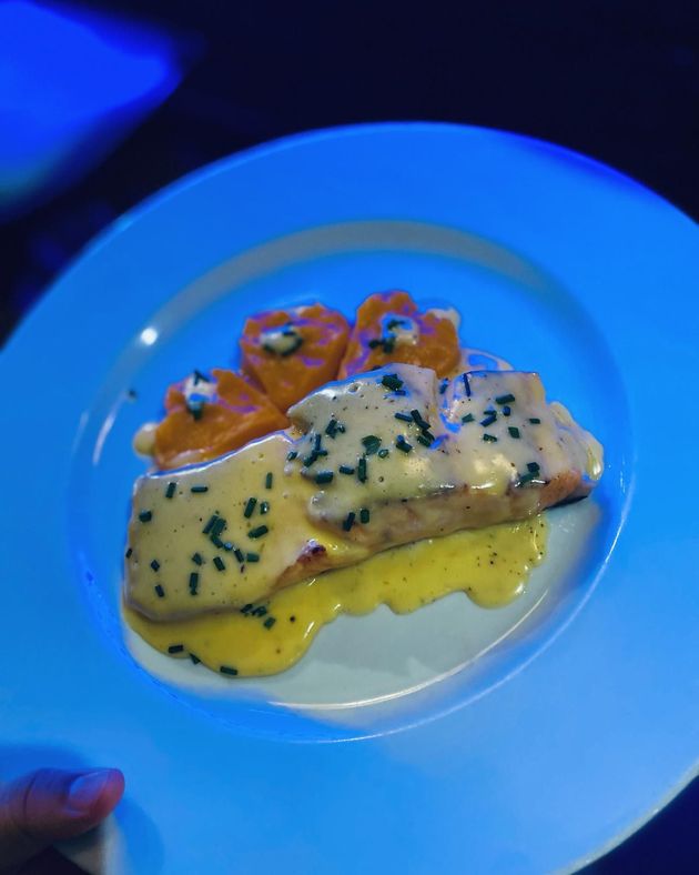 Filete de salmón con salsa y guarnición de albóndigas de naranja en un plato azul.