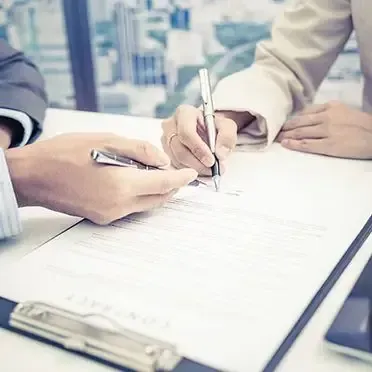 Un hombre y una mujer están firmando un documento en un portapapeles.