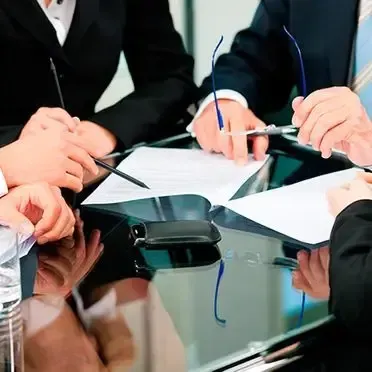 Un grupo de personas están sentadas alrededor de una mesa escribiendo en papeles.