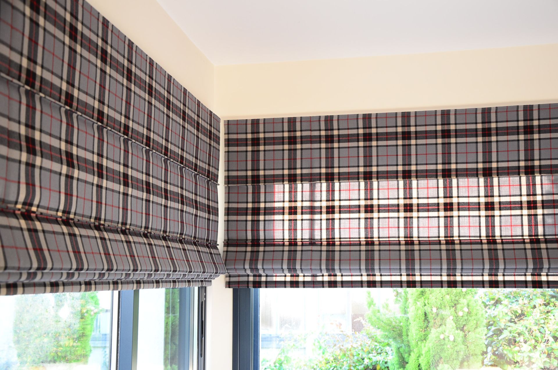 Stores bateaux devant baies vitrées avec tissu à motif écossais à dominante rouge et gris