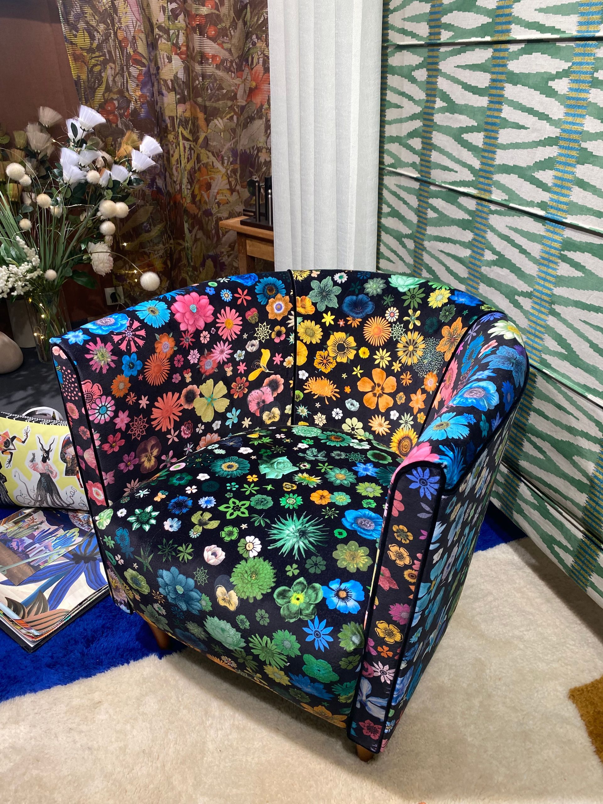 Fauteuil fond noir grandement dominé par des motifs de fleurs multicolores