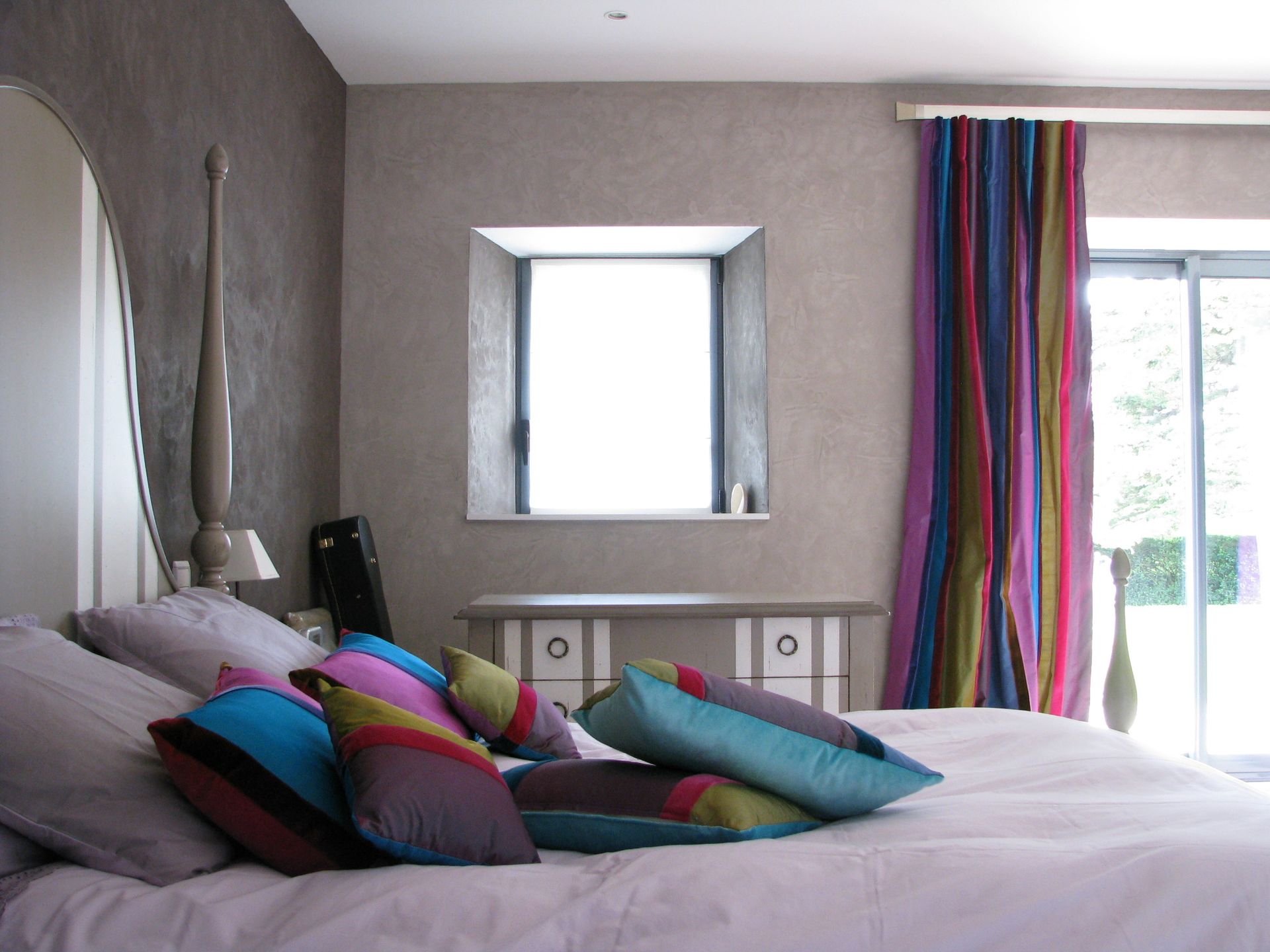 Chambre à coucher avec dessus de lit blanc, coussins, rideaux plis piqués multicolores assortis