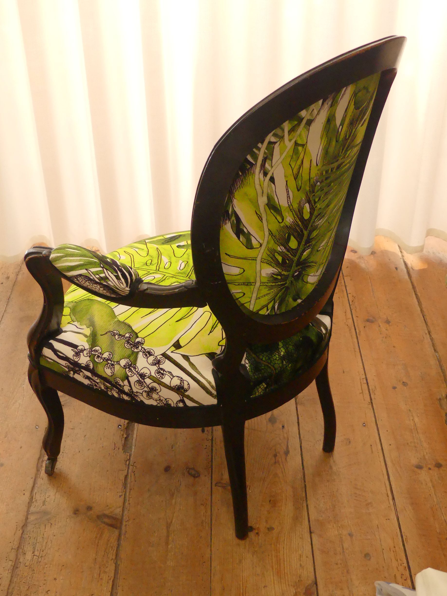 Fauteuil bois noir, les accoudoirs dossier et assise sont recouverts d'un tissu Christian Lacroix avec motifs de feuilles tropicales à couleurs jaune et verte dominantes