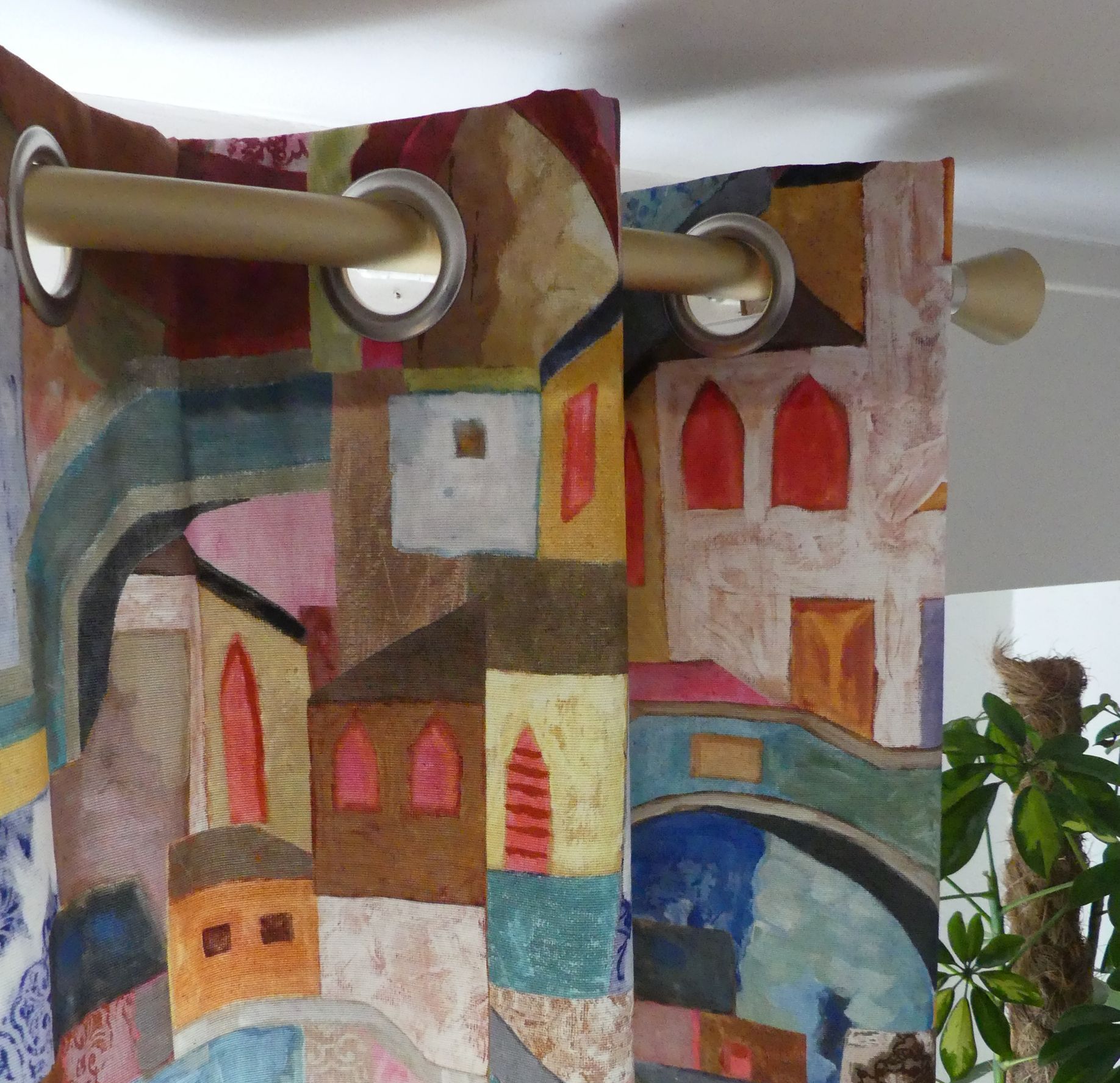 Tringle à rideau laiton brossé avec rideau à œillets,  le tissu du rideau représente un village peint de toutes les couleurs