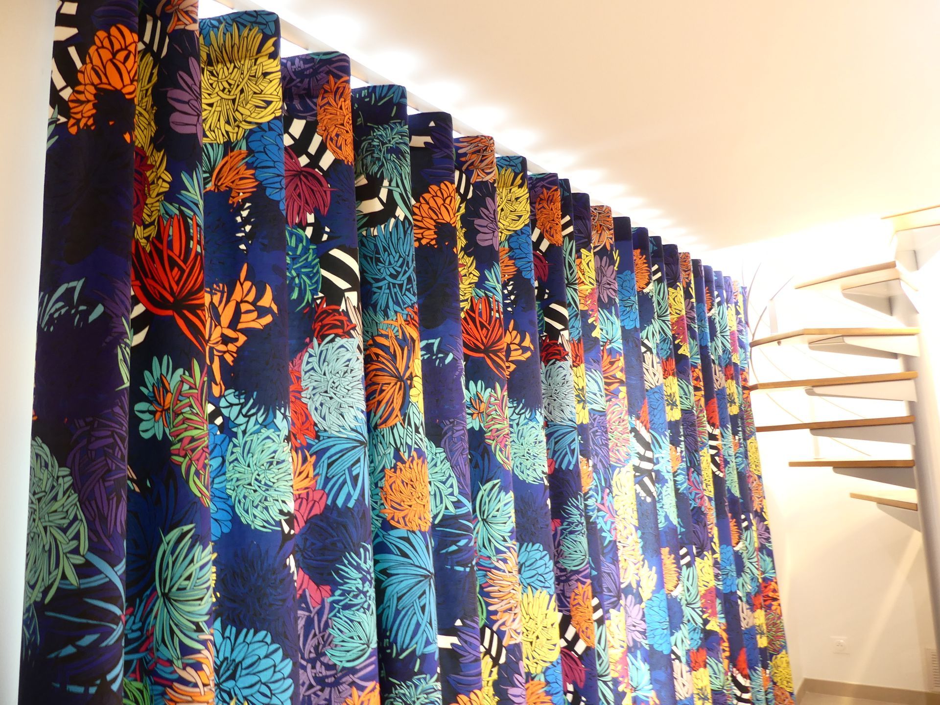 Rideau wave fond bleu marine avec décor sous-marin multicolore, escaliers moderne bois et métal au second plan