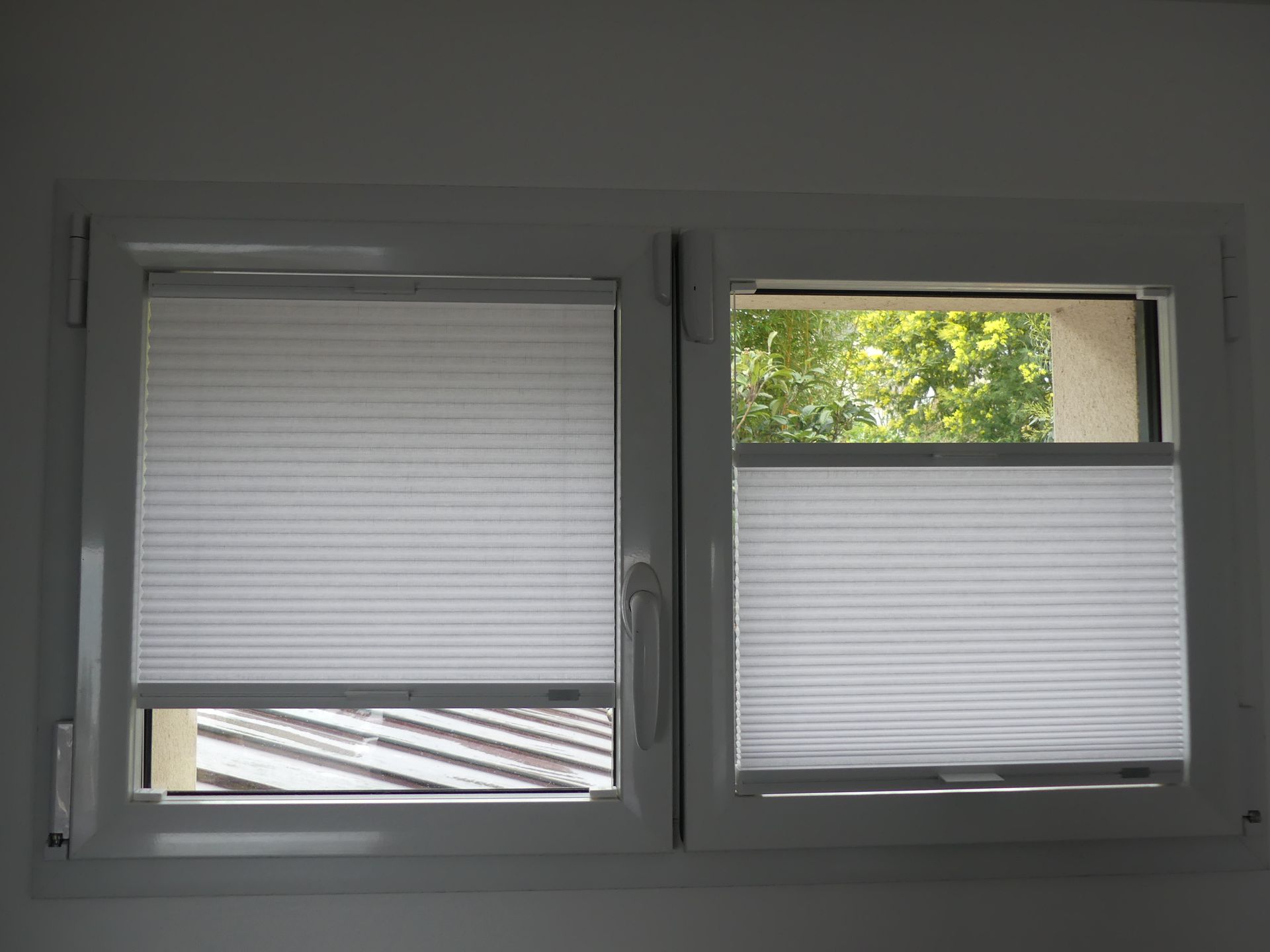 Deux battants de fenêtre partiellement occultés par des stores plissés
