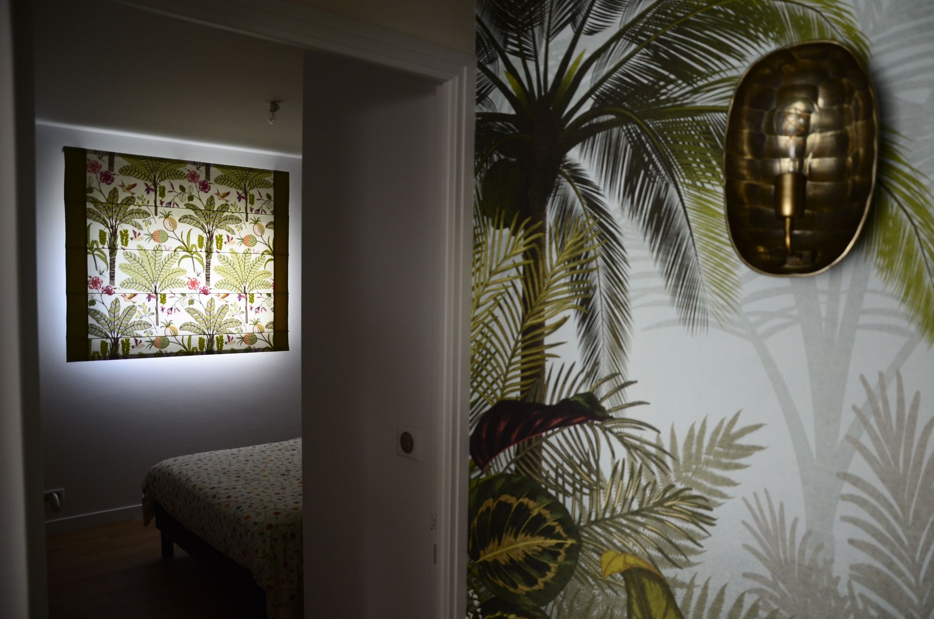 Couloir avec papier peint ambiance tropicale, chambre à coucher au second plan avec stores bateaux assortis