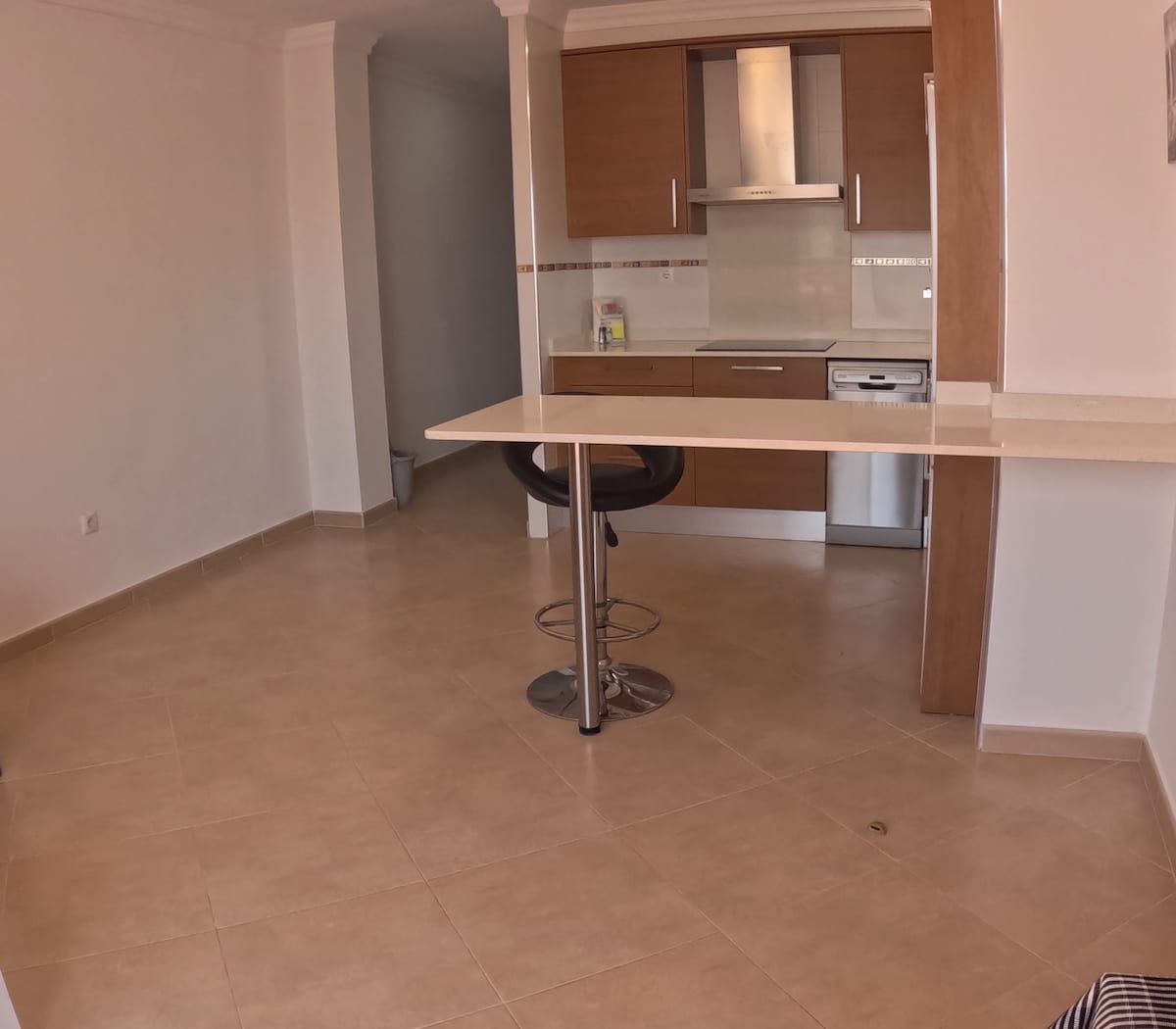 Área de cocina con barra de desayuno y un taburete individual.