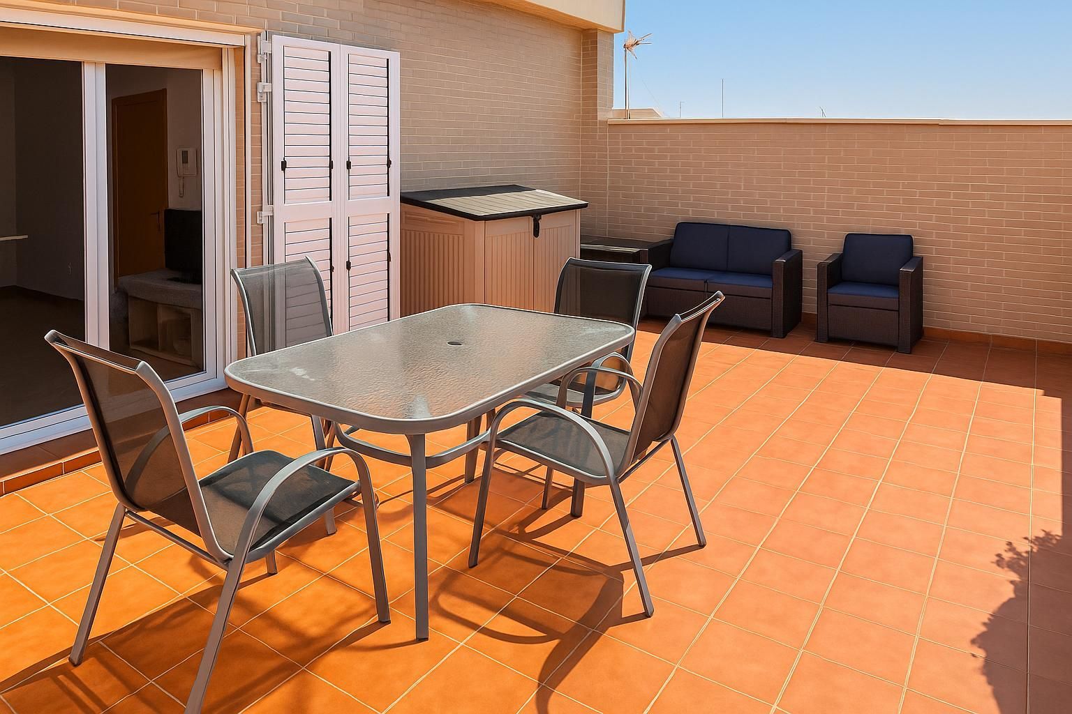Terraza al aire libre con mesa de cristal, sillas, jacuzzi y asientos.