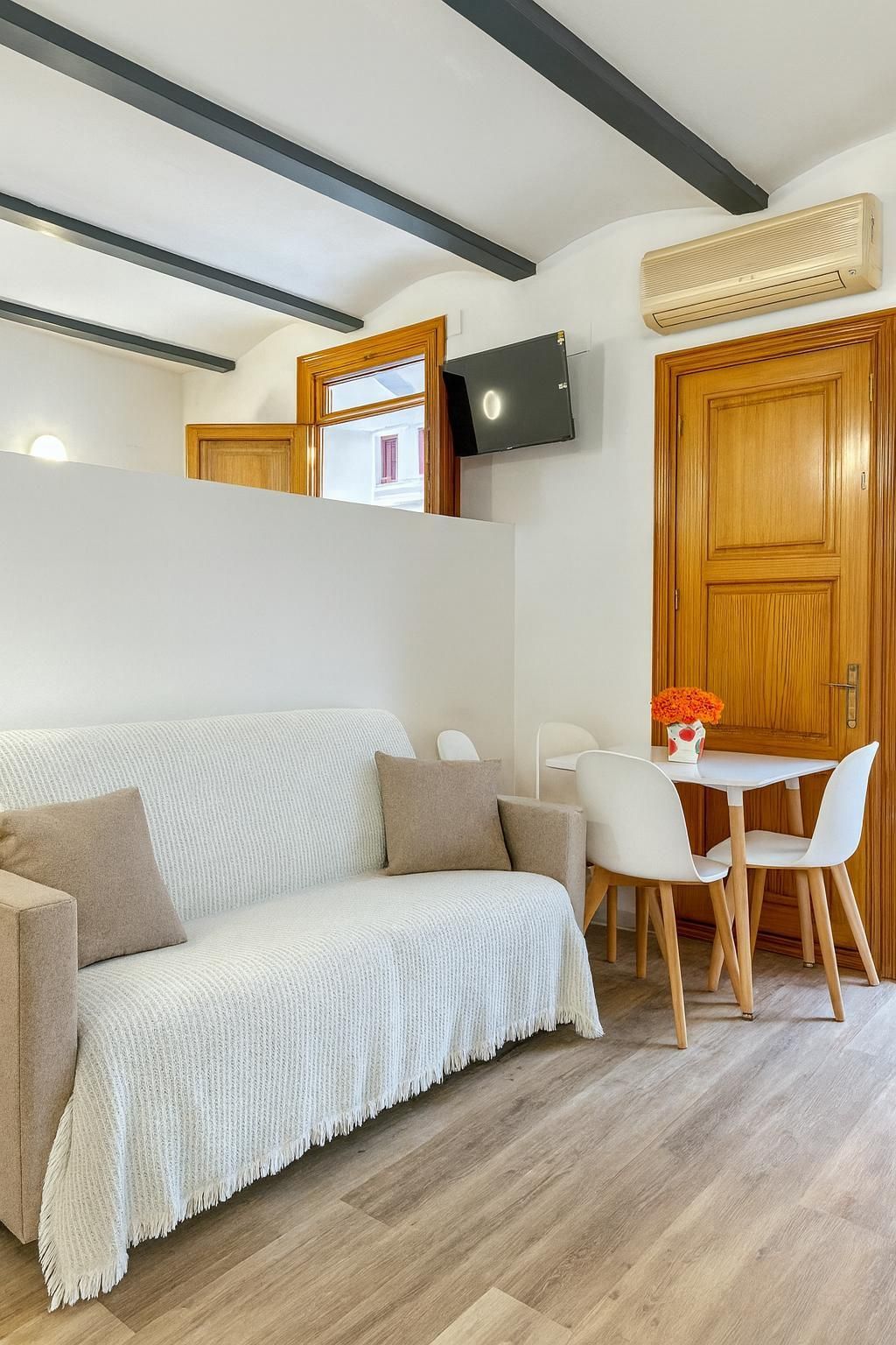 Acogedor apartamento tipo estudio con sofá, mesa pequeña y puerta de madera.