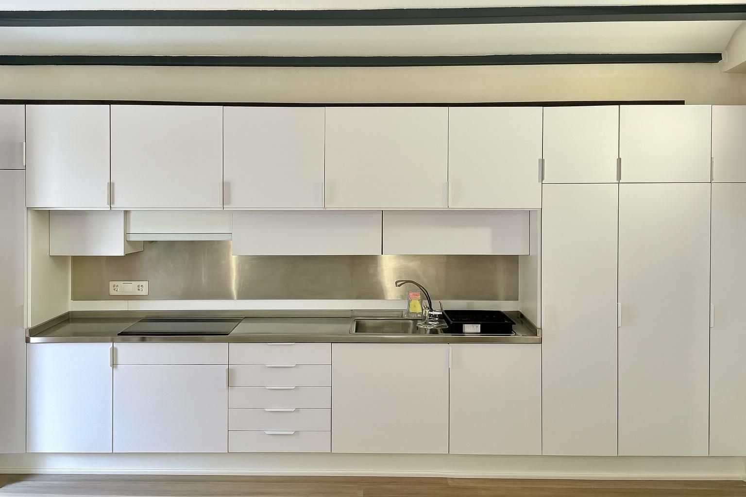 Cocina moderna blanca con salpicadero y encimeras de acero inoxidable.