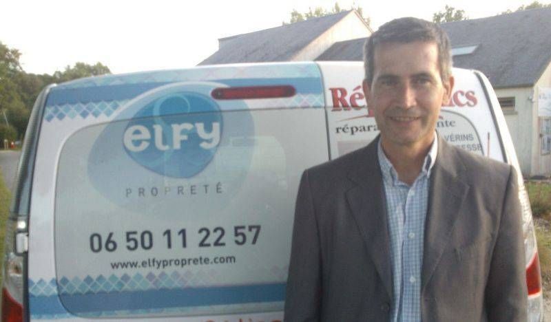 Gérant se tenant devant un camion avec le logo de l'entreprise