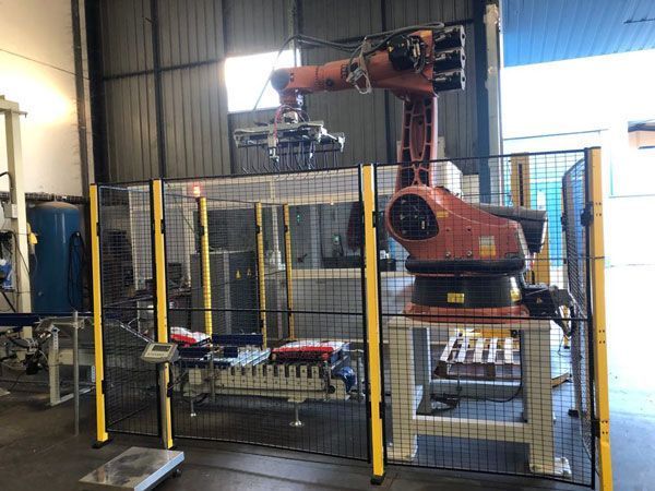 Un brazo robótico está detrás de una valla en una fábrica.