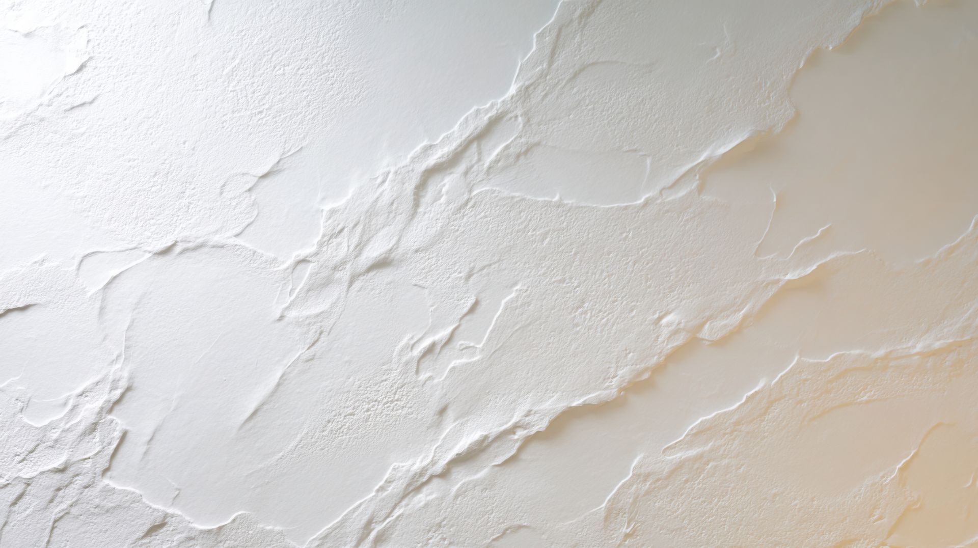 Mur en plâtre texturé blanc et beige avec de subtiles touches fluides.