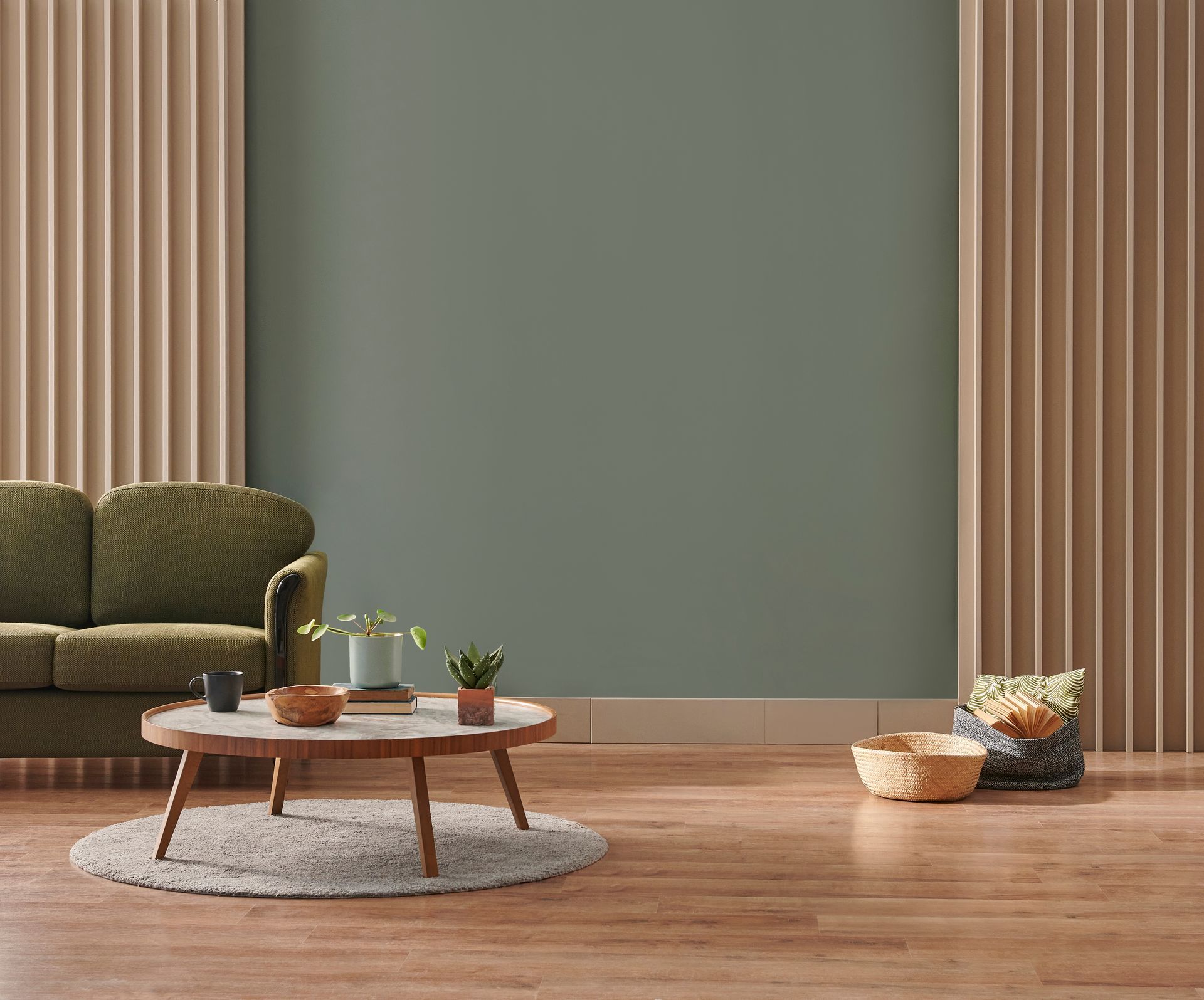 Salon minimaliste avec canapé olive, table basse ronde, tapis et paniers tressés sur parquet.