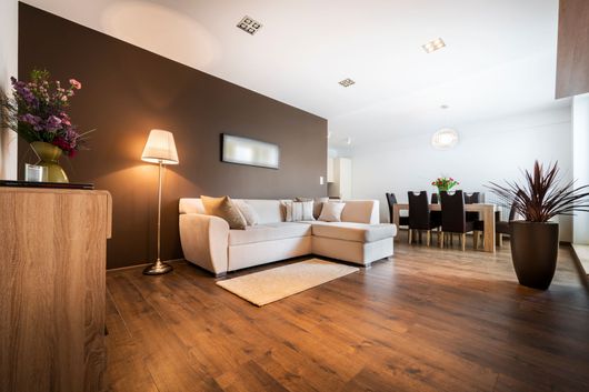 Salon moderne à aire ouverte avec canapé blanc, lampadaire, table à manger et parquet.