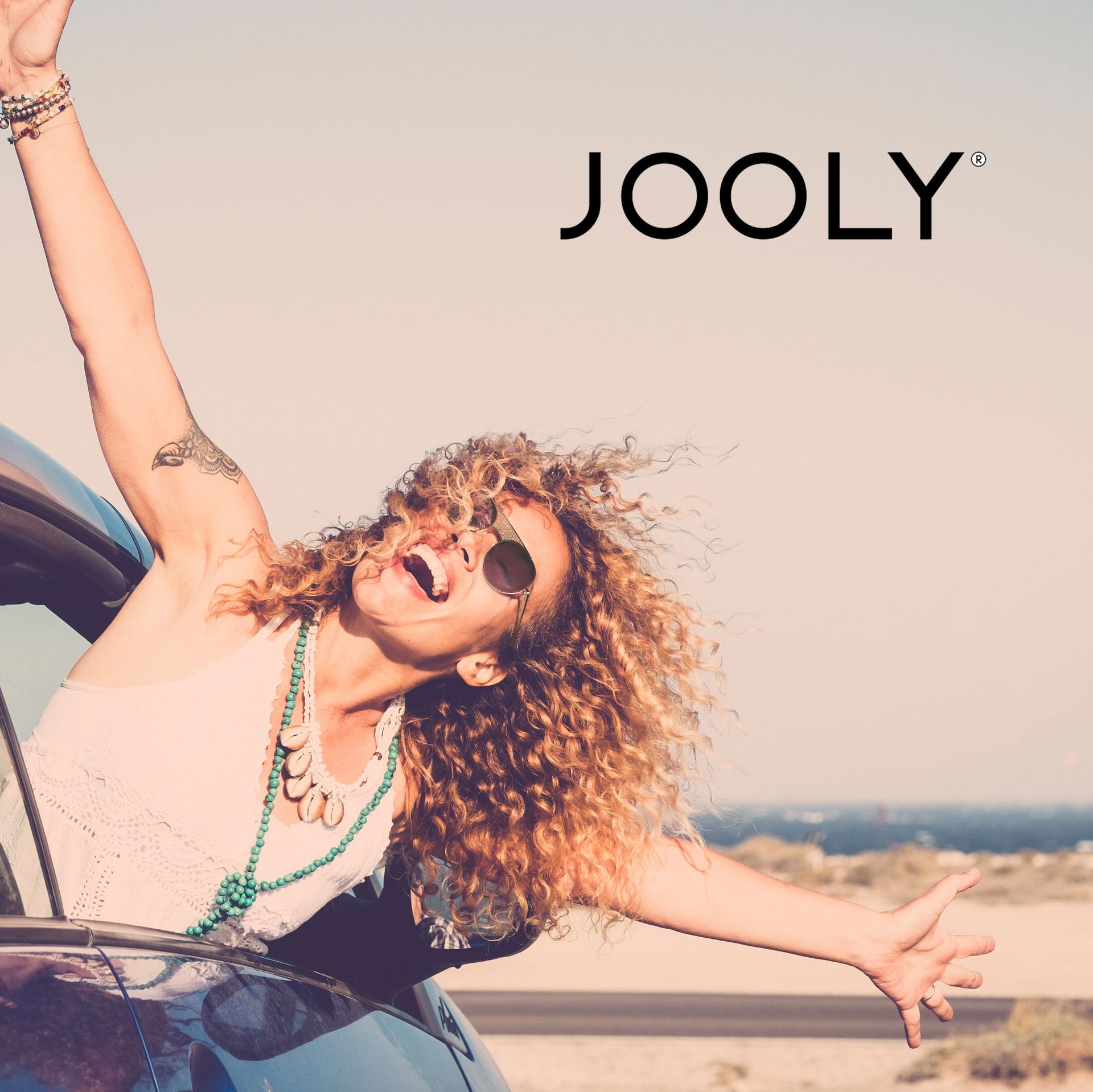 Une femme est assise dans une voiture avec les bras tendus devant un logo joyeux