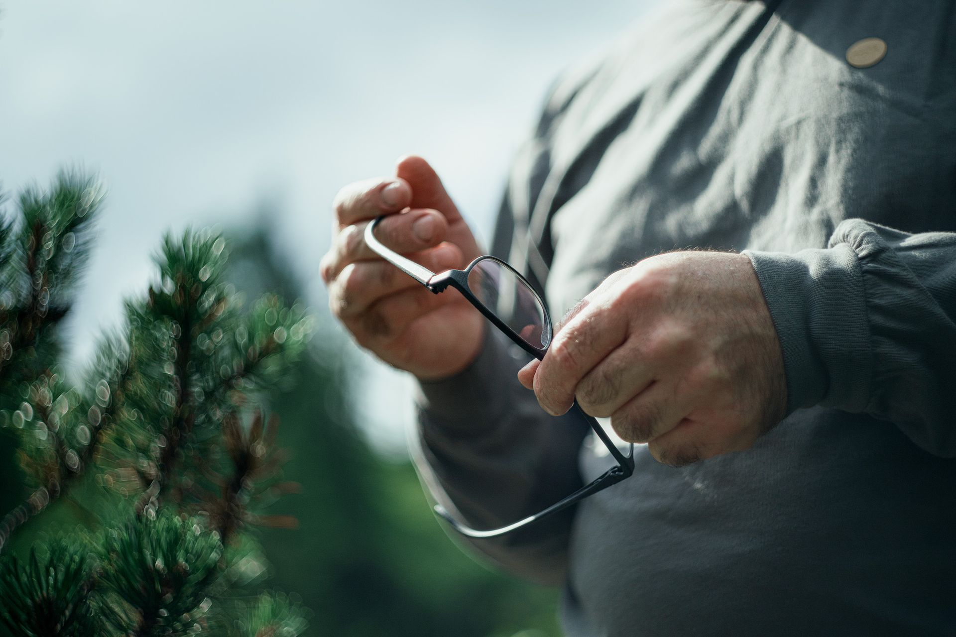 Un homme tient une paire de lunettes dans ses mains.