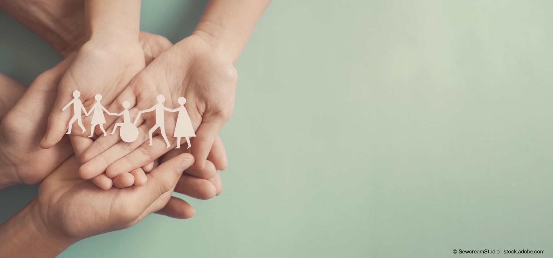 Zwei paar Hände halten Menschen aus Papier in der Hand