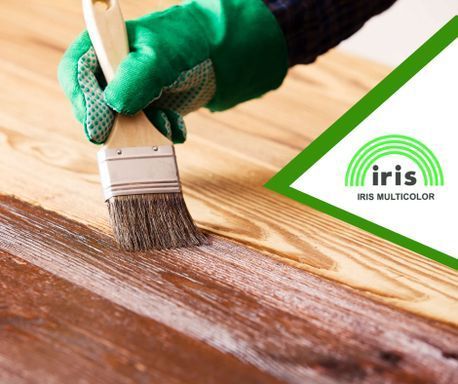 Una persona que lleva un guante verde está pintando una superficie de madera con un pincel.