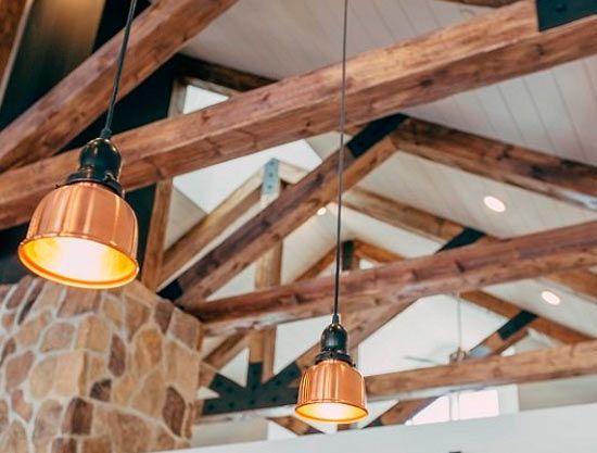 Un techo con vigas de madera y luces de cobre colgando de él.