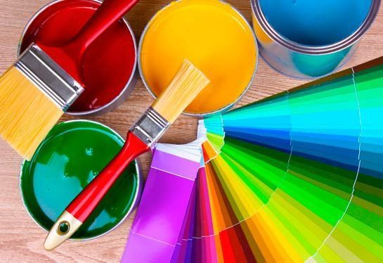 Hay muchos colores diferentes de pintura y pinceles sobre la mesa.