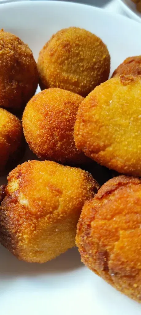 Croquetas fritas doradas sobre un plato blanco.