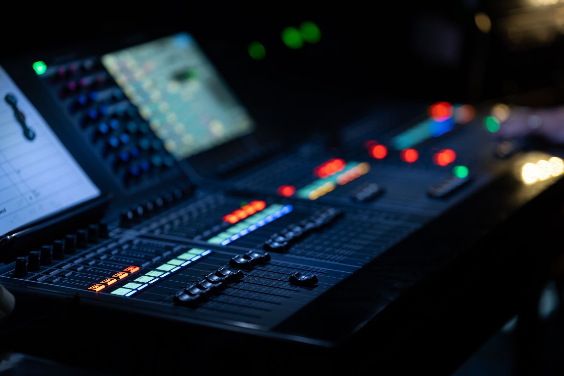 Console de mixage audio avec boutons et curseurs lumineux dans un studio sombre.