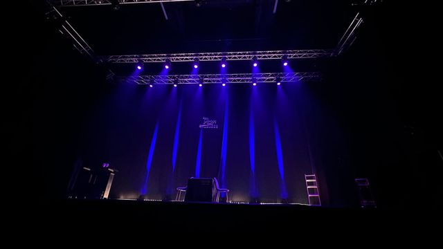 Grande console de mixage audio avec des rangées de commandes et une scène en arrière-plan.