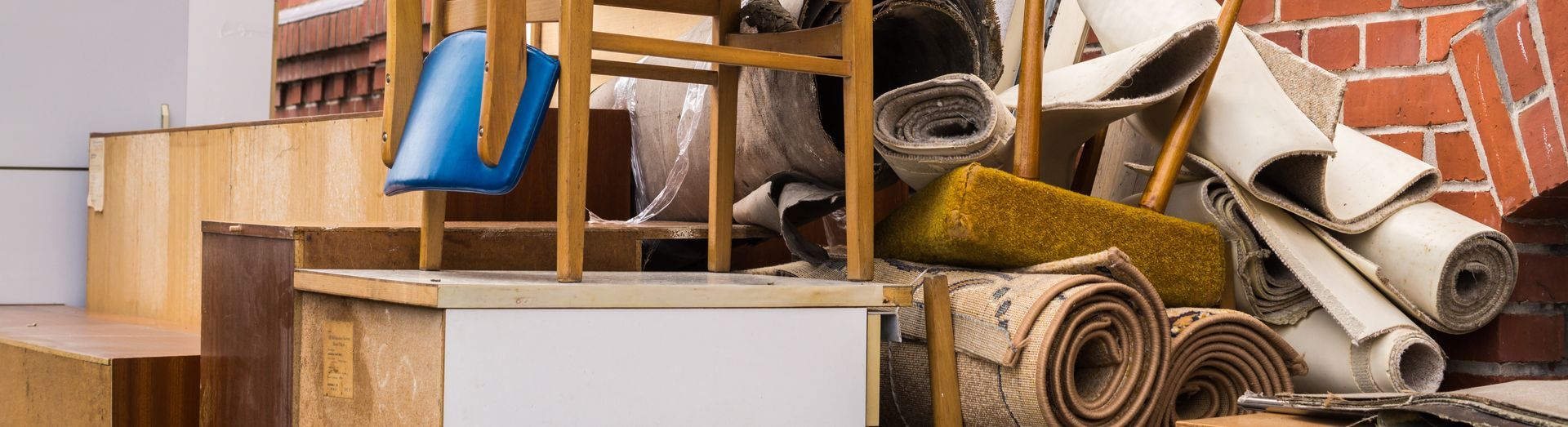 Des cartons de déménagement empilés, des tapis roulés et des meubles emballés dans un espace de stockage