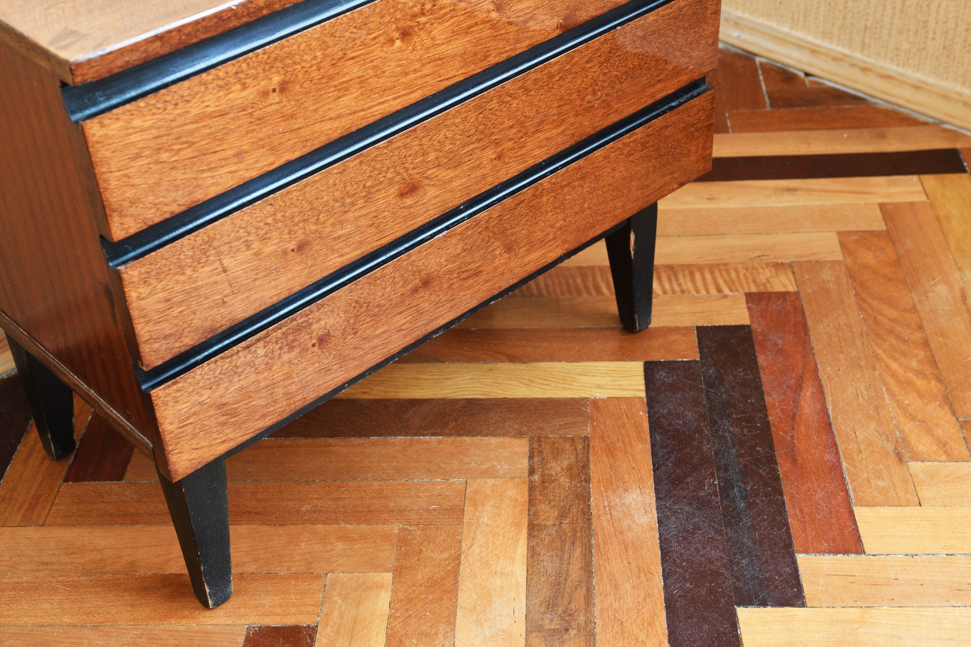 Chiffonnier en bois posé sur un parquet en chevron.