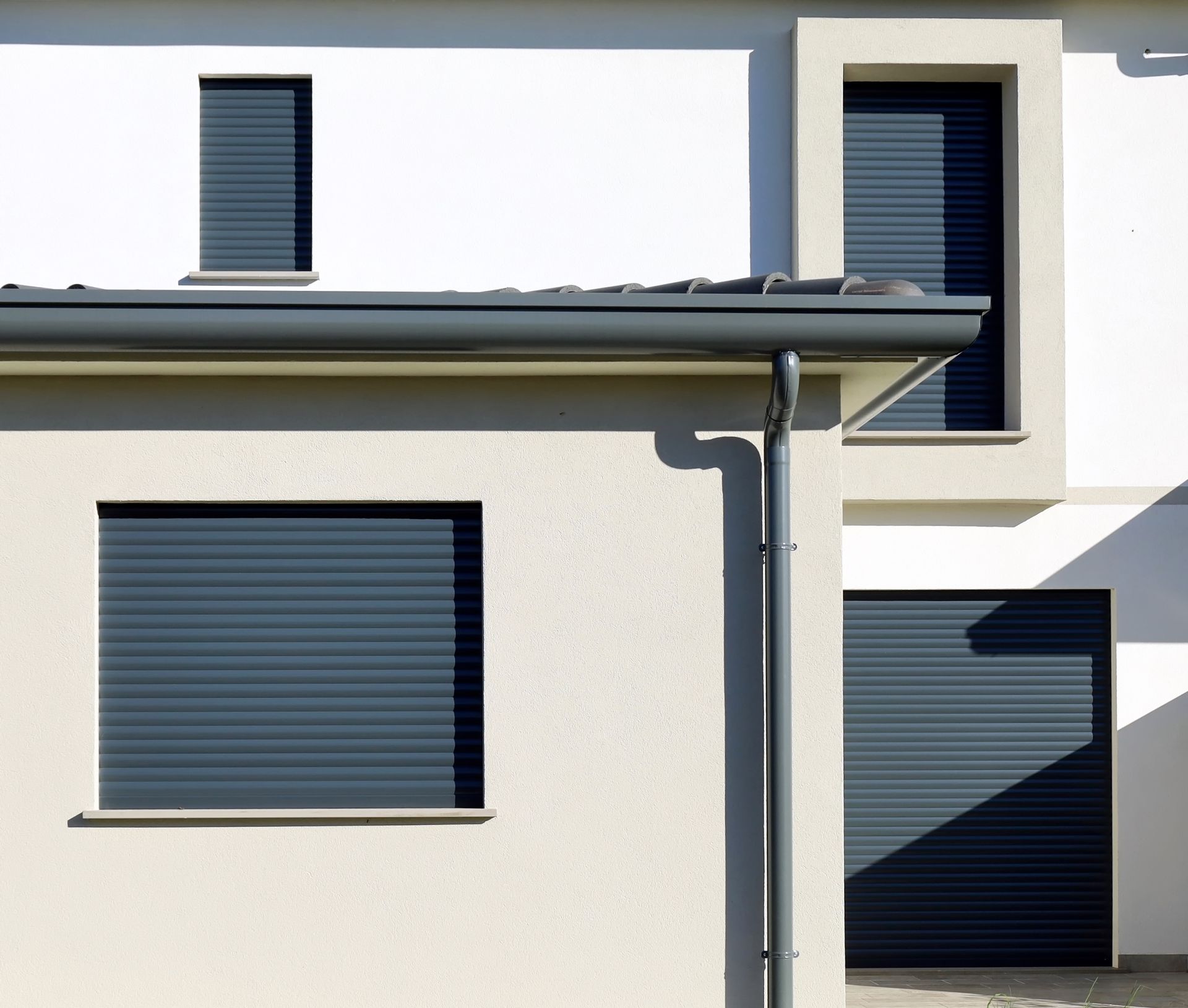 Façade moderne de maison blanche avec des volets et des fenêtres bleu foncé, vue de près en plein jour