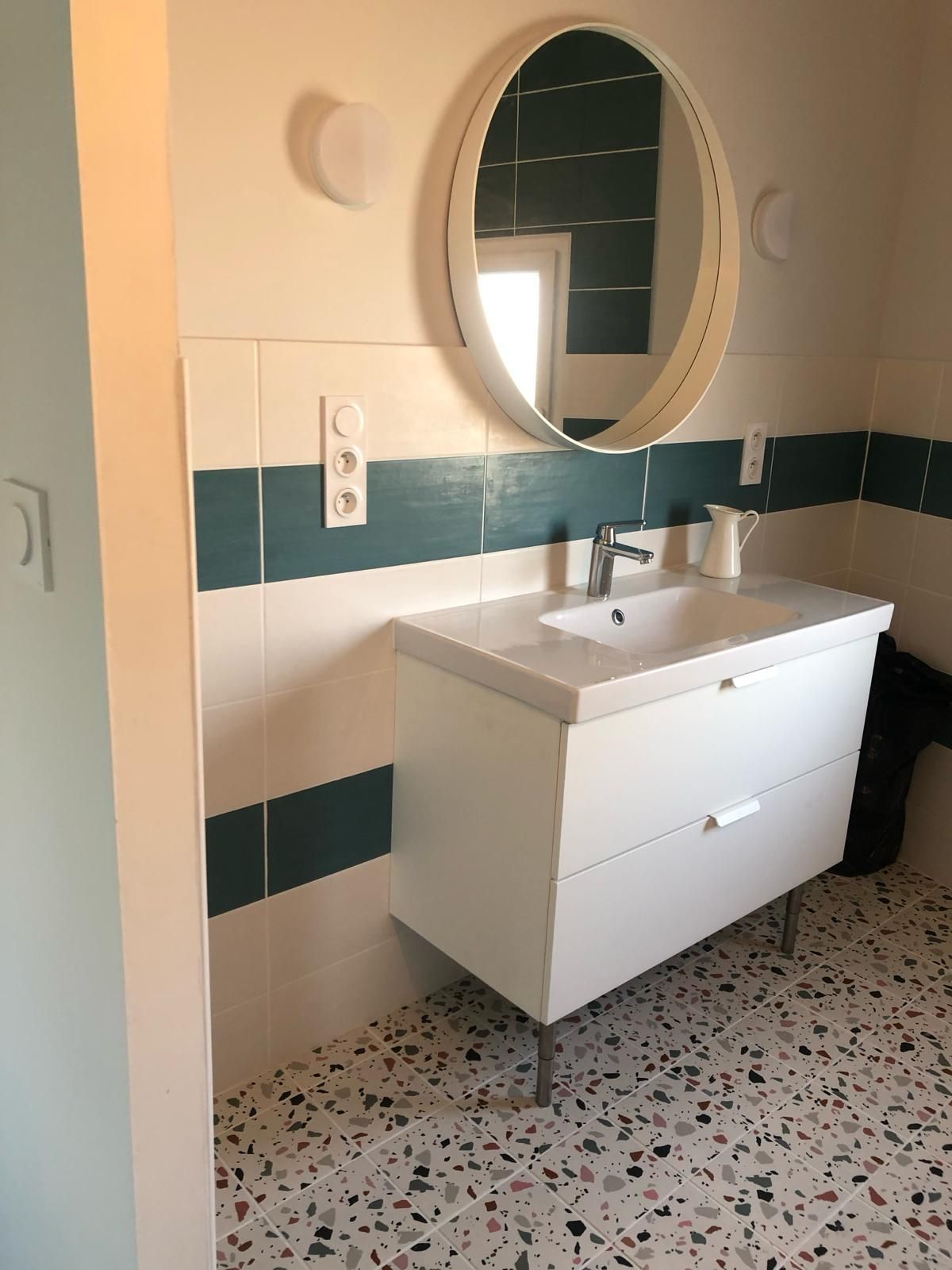 Photo d'un lavabo avec un miroir rond et un mur bleu et blanc