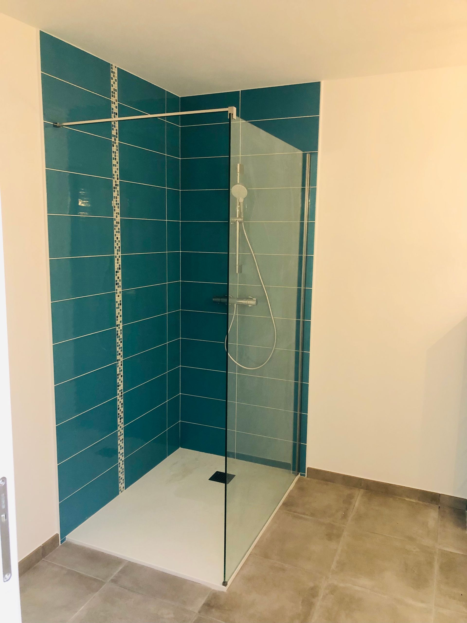 Photo d'une douche avec les paroies en verre et un mur bleu