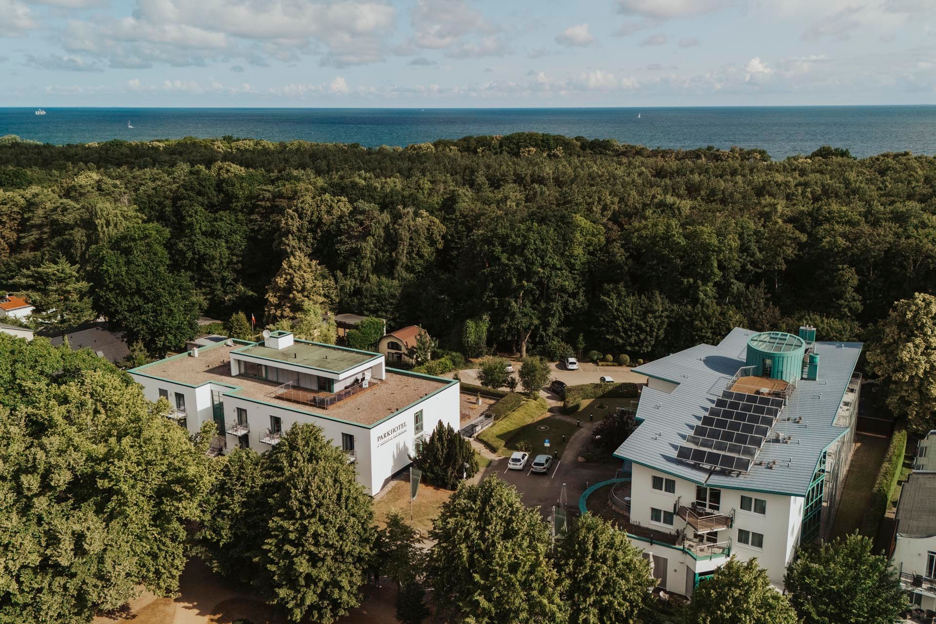 Elegantes weißes Gebäude mit Turm; rote Fahnen, Sitzbereich im Freien und Schilder an einem sonnigen Tag.