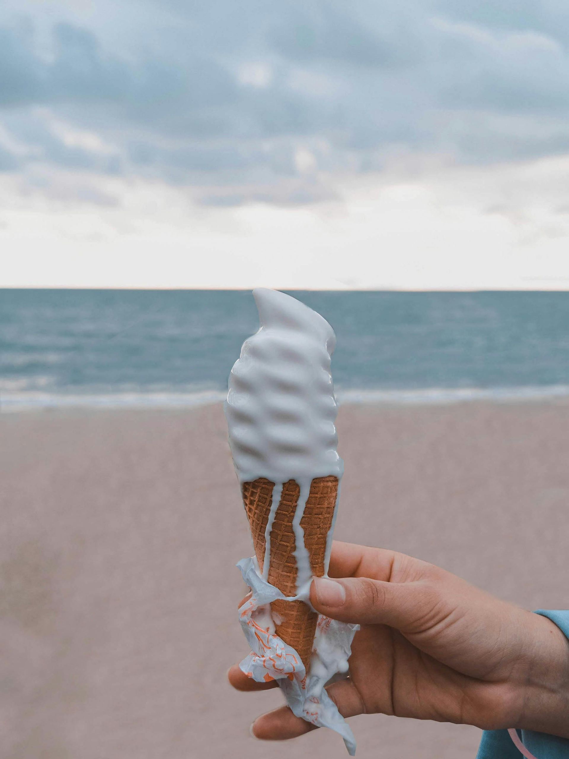 Eine Möwe im Flug über einem Strand, im Vordergrund ein leuchtend orangefarbenes Strandstuhldach vor blauem Himmel.