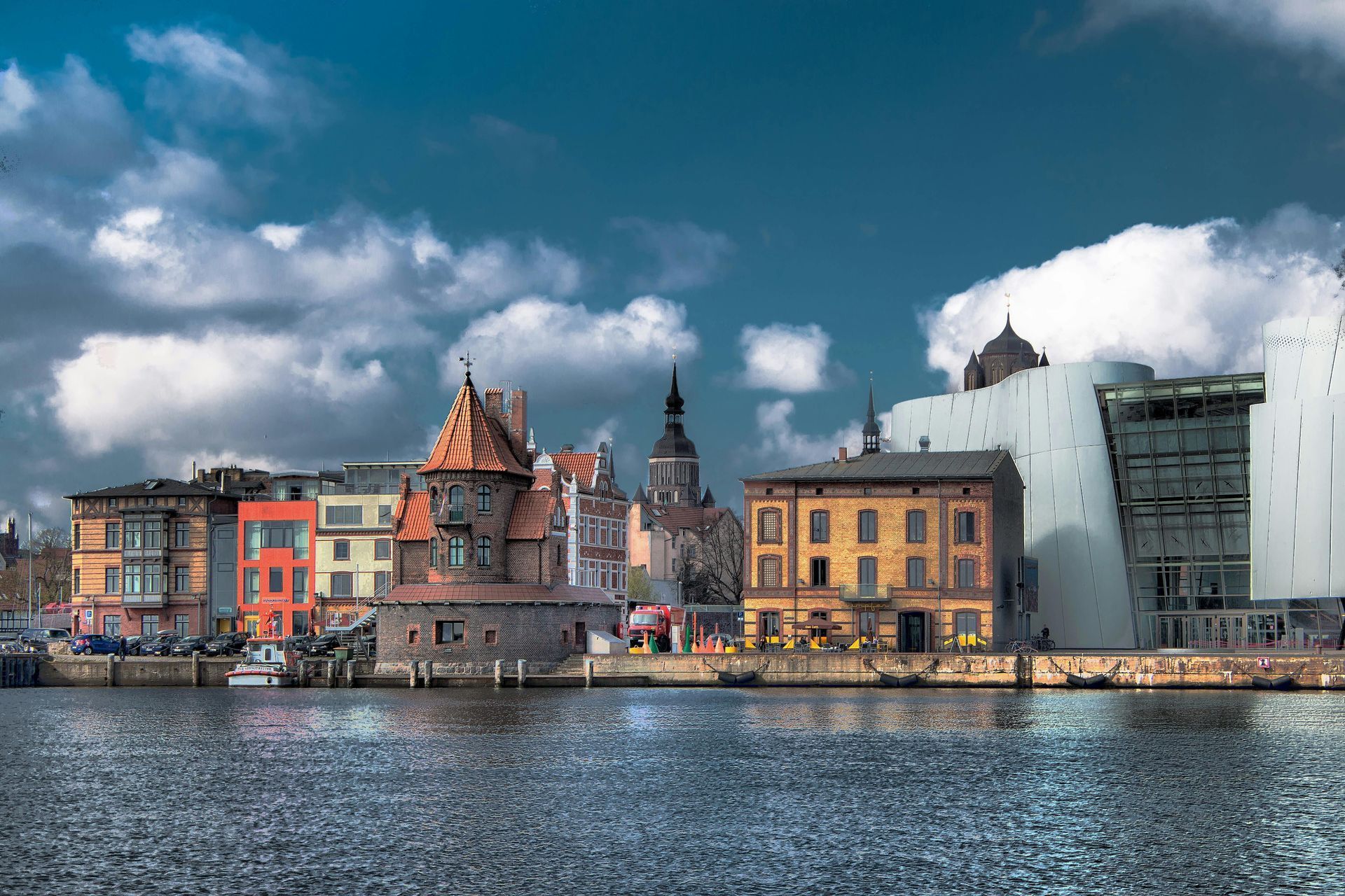 Farbenfrohe Gebäude am Wasser unter einem bewölkten Himmel, die sich im ruhigen Wasser spiegeln
