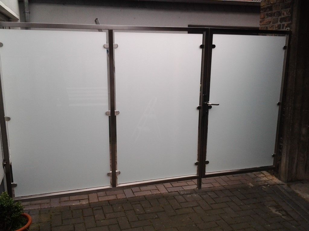 Auf einem Gehweg aus Backsteinen steht ein Zaun aus Milchglas.