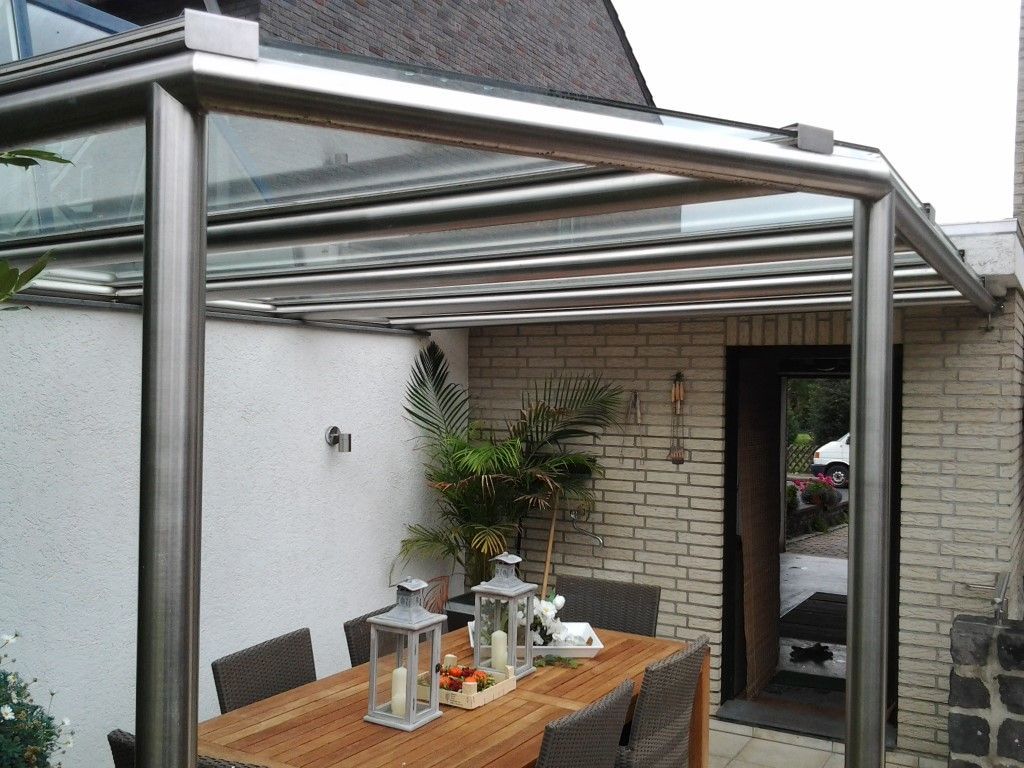 Ein Holztisch mit Laternen darauf unter einem Glasdach.