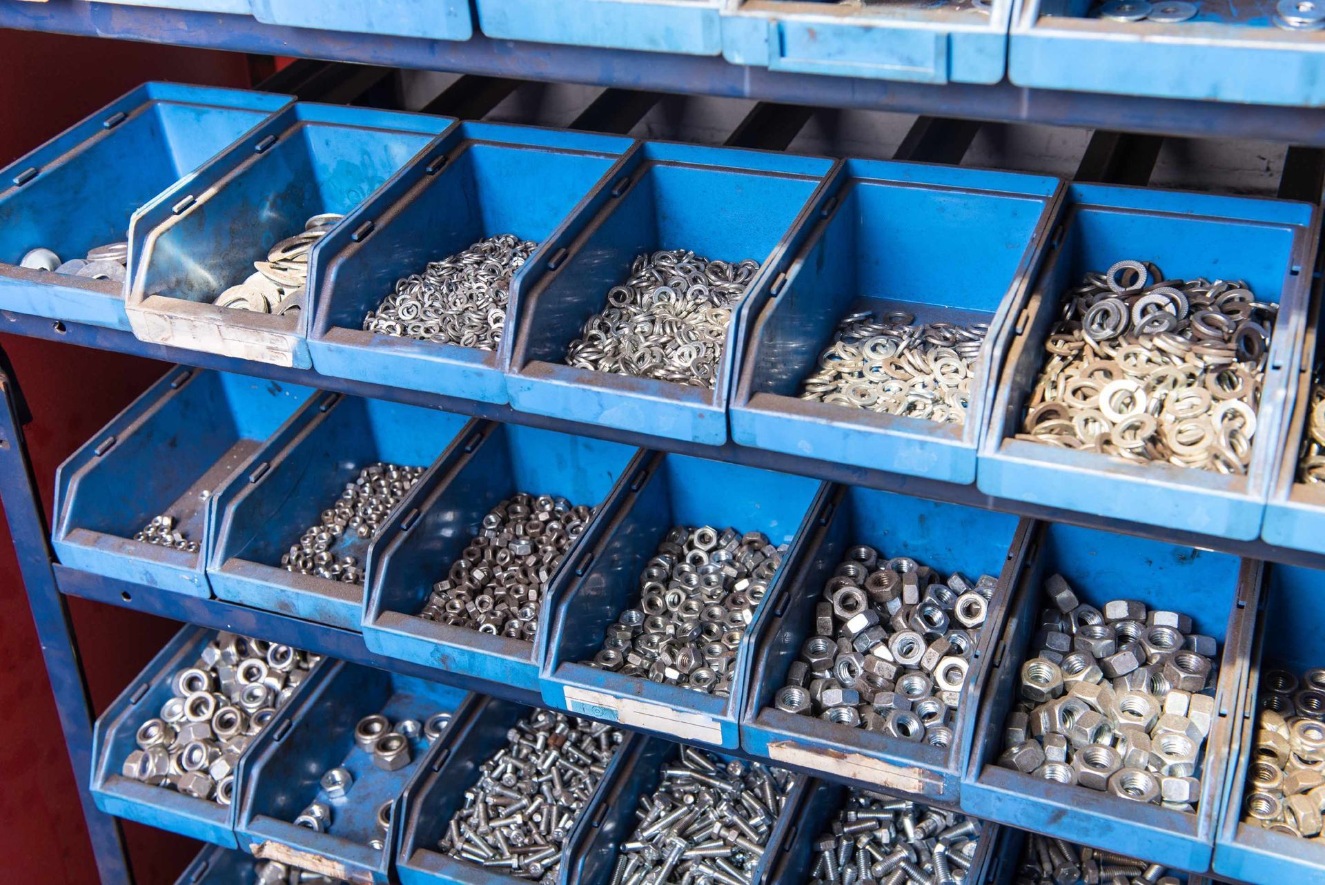 Ein Regal voller blauer Behälter mit Schrauben und Muttern