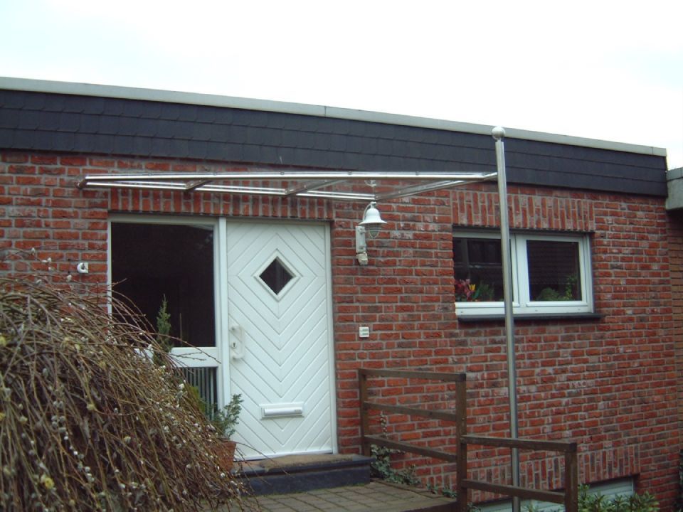 Ein Backsteinhaus mit einer weißen Tür und einem schwarzen Dach