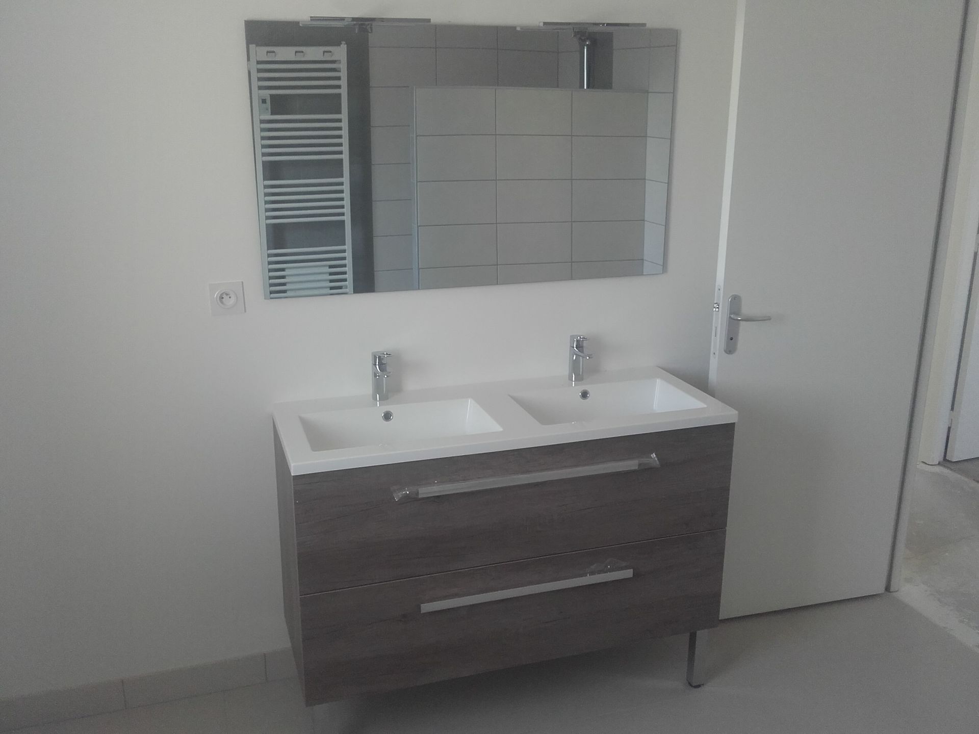 Meuble-lavabo moderne avec double vasque, armoire en bois foncé, miroir et mur carrelé blanc