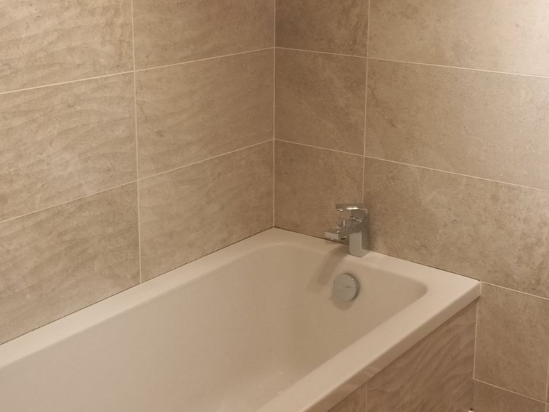 Salle de bains carrelée beige avec baignoire blanche et robinet chromé. Bayeux Salle de bains carrelée beige avec baignoire blanche et robinet chromé.